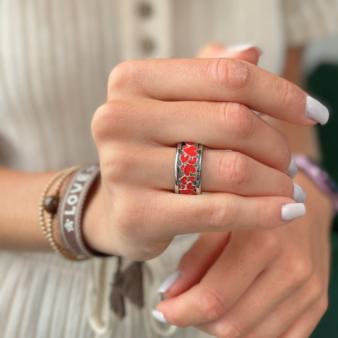 bague mood en argent avec des coeurs rouges portée par une femme habit blanc et ongles et bracelets